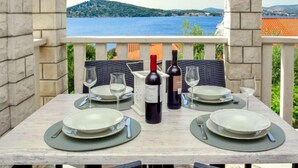 An outdoor dining area with a table set for two, overlooking a scenic view of a lake and hills.