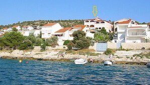A coastal area with white buildings, a rocky shoreline, and boats in the water.