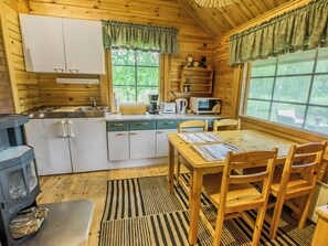 A cozy cabin interior with a kitchen, dining area, and a wood stove. - Meripoika by Interhome (Pöytyä)