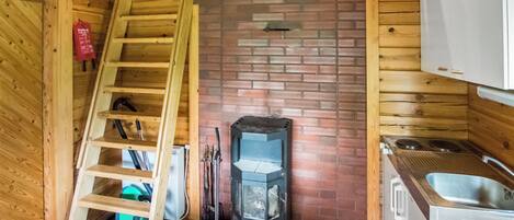 Een houten chalet met een keukenhoek, een open haard en een houten trap.