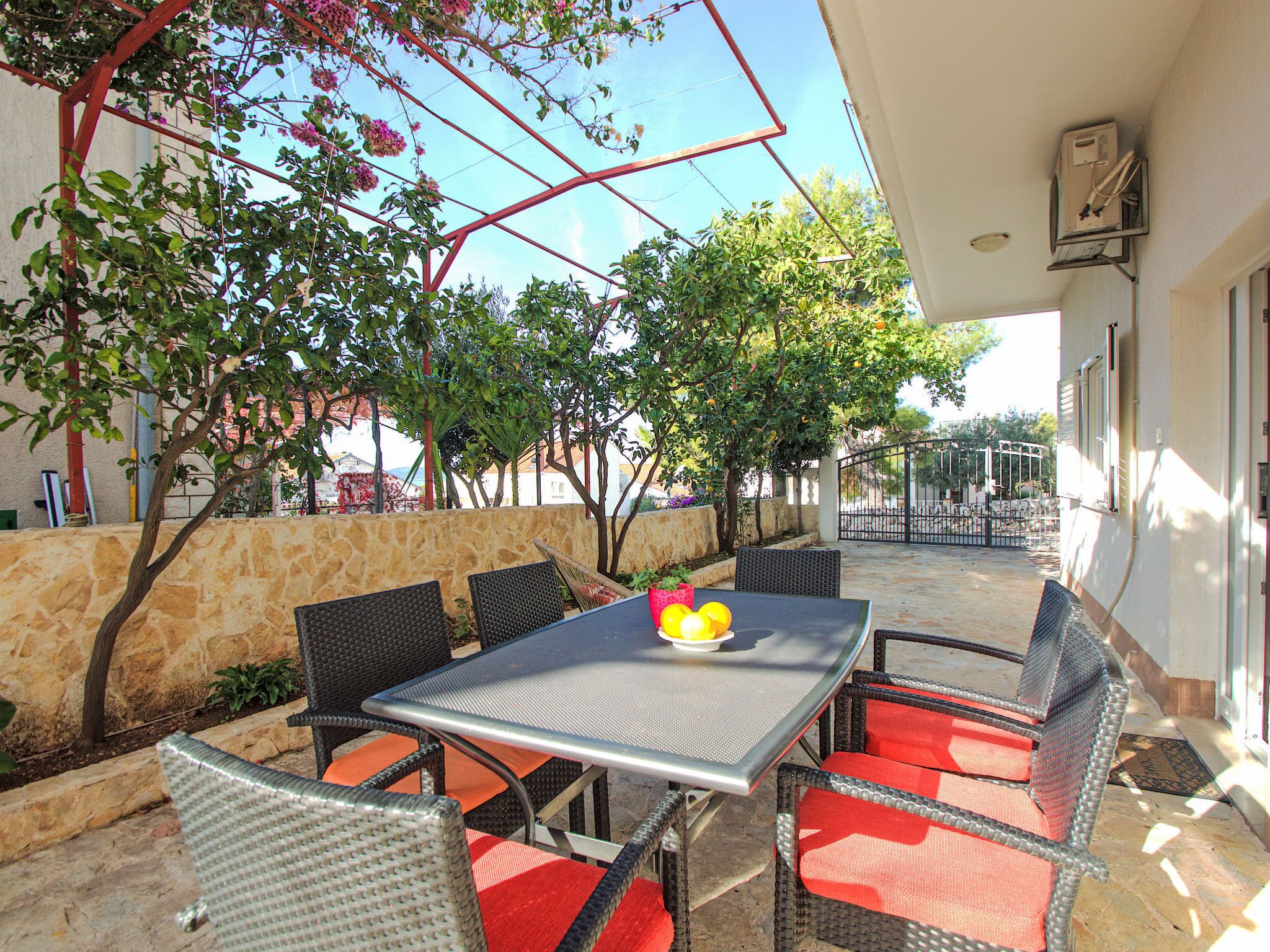 An outdoor patio with a table and chairs, surrounded by stone walls and trees.