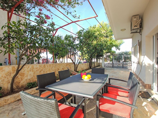 An outdoor patio with a table and chairs, surrounded by stone walls and trees.