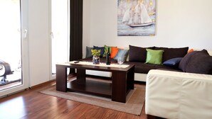 A living room with a dark wooden coffee table, a sofa with colorful cushions, and a painting of a sailboat on the wall. - Vila SanAdrija (Trogir)