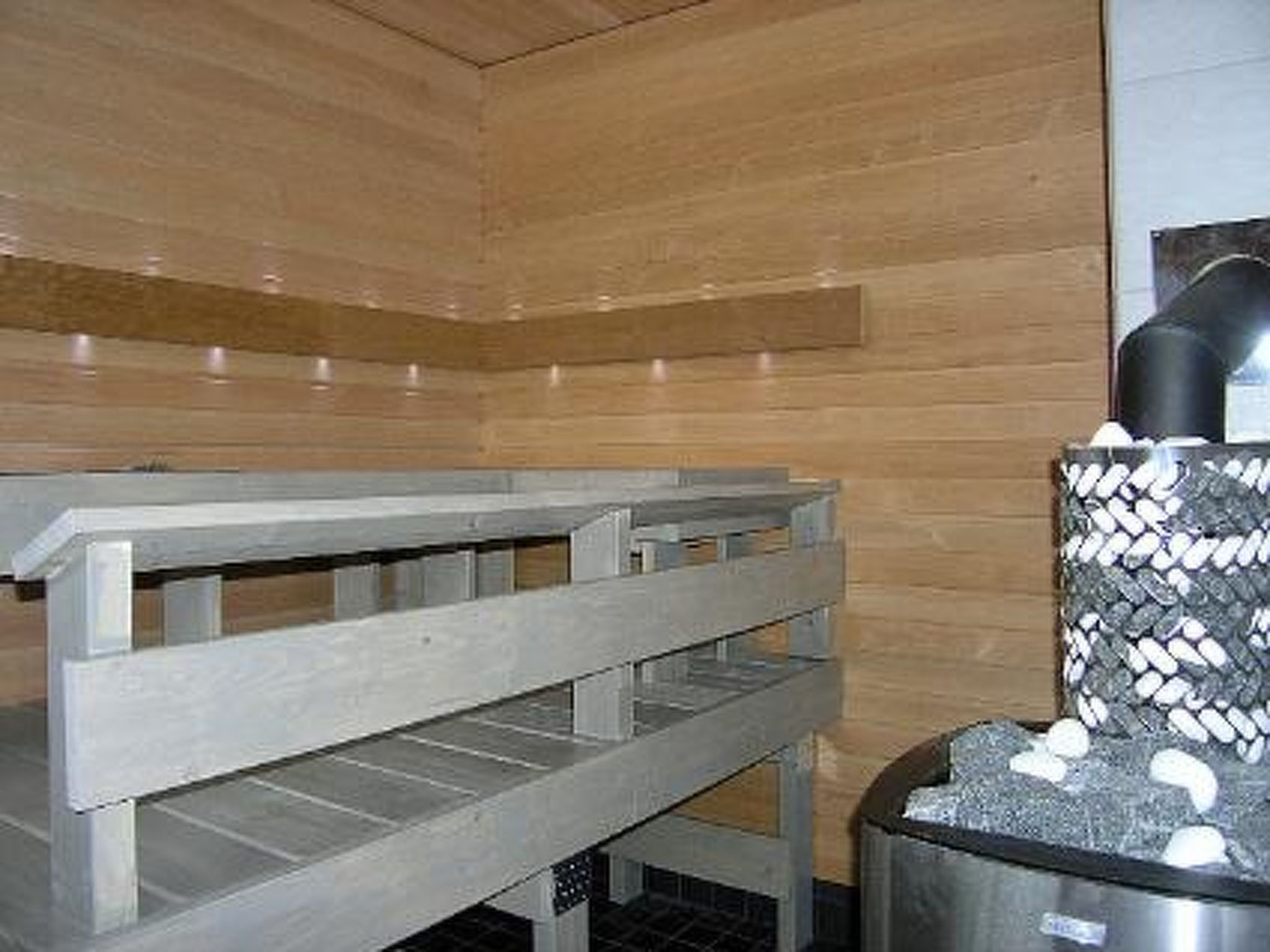 Un sauna con bancos y pared de piedra.