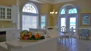 A kitchen with a central island, large windows, and a view of the ocean.