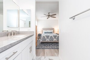 Un baño moderno con un espejo grande, un tocador con lavabo y un ventilador de techo.