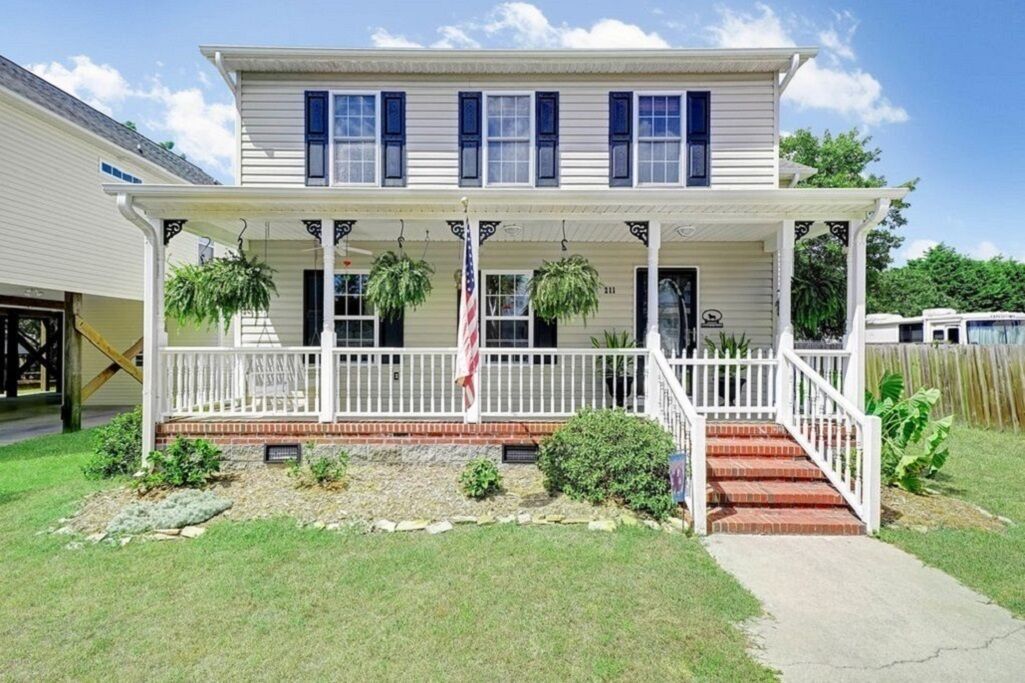 A two-story house with a porch, a front yard, and a mailbox.