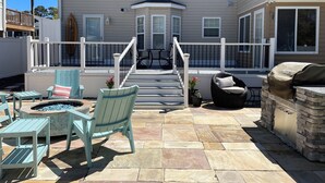 A covered patio with outdoor furniture, a fire pit, and a barbecue grill.