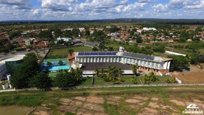 Um hotel grande com piscina, painéis solares e vista da região ao redor.