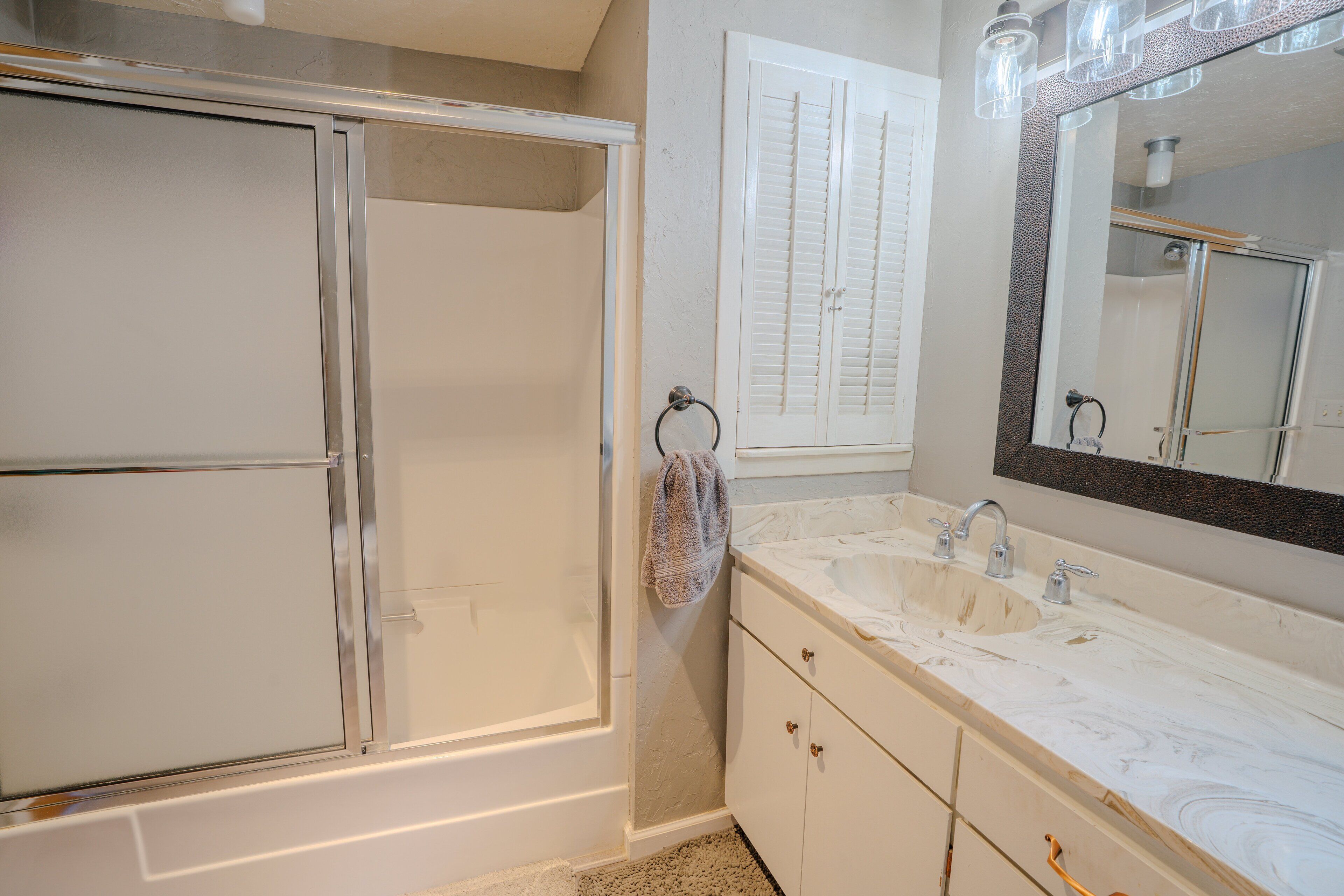 A bathroom with a glass shower enclosure, a double sink vanity, and a large mirror.