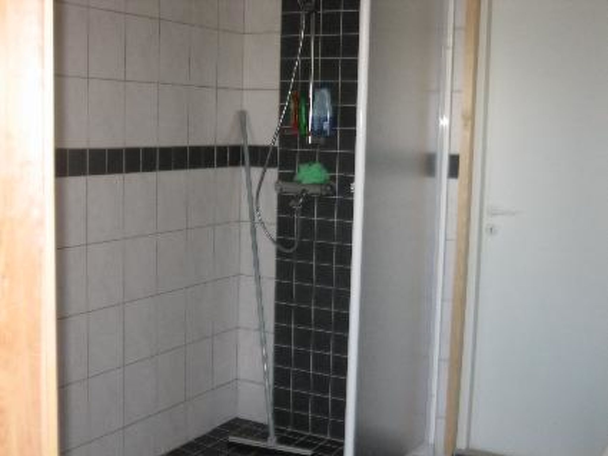 A shower area with tiled walls, a metal shower enclosure, and a door.
