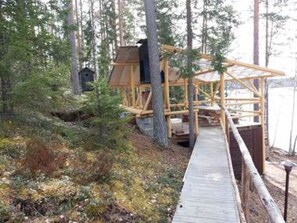 A wooden deck leading to a rustic cabin structure surrounded by trees. - Käkiharju by Interhome (Sulkava)
