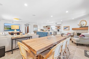 A modern living room with a wooden coffee table, wicker chairs, a sofa, and a TV. - Luxury Single-Family Vacation Home | Roof-Top Deck and A/C | The Perfect Vacation Headquarters! (Newport Beach)