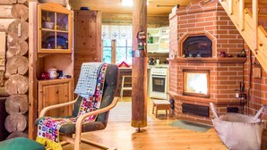 Interior acogedor de una cabaña con piso de madera, chimenea de ladrillo, sillón mecedor y escalera de madera.