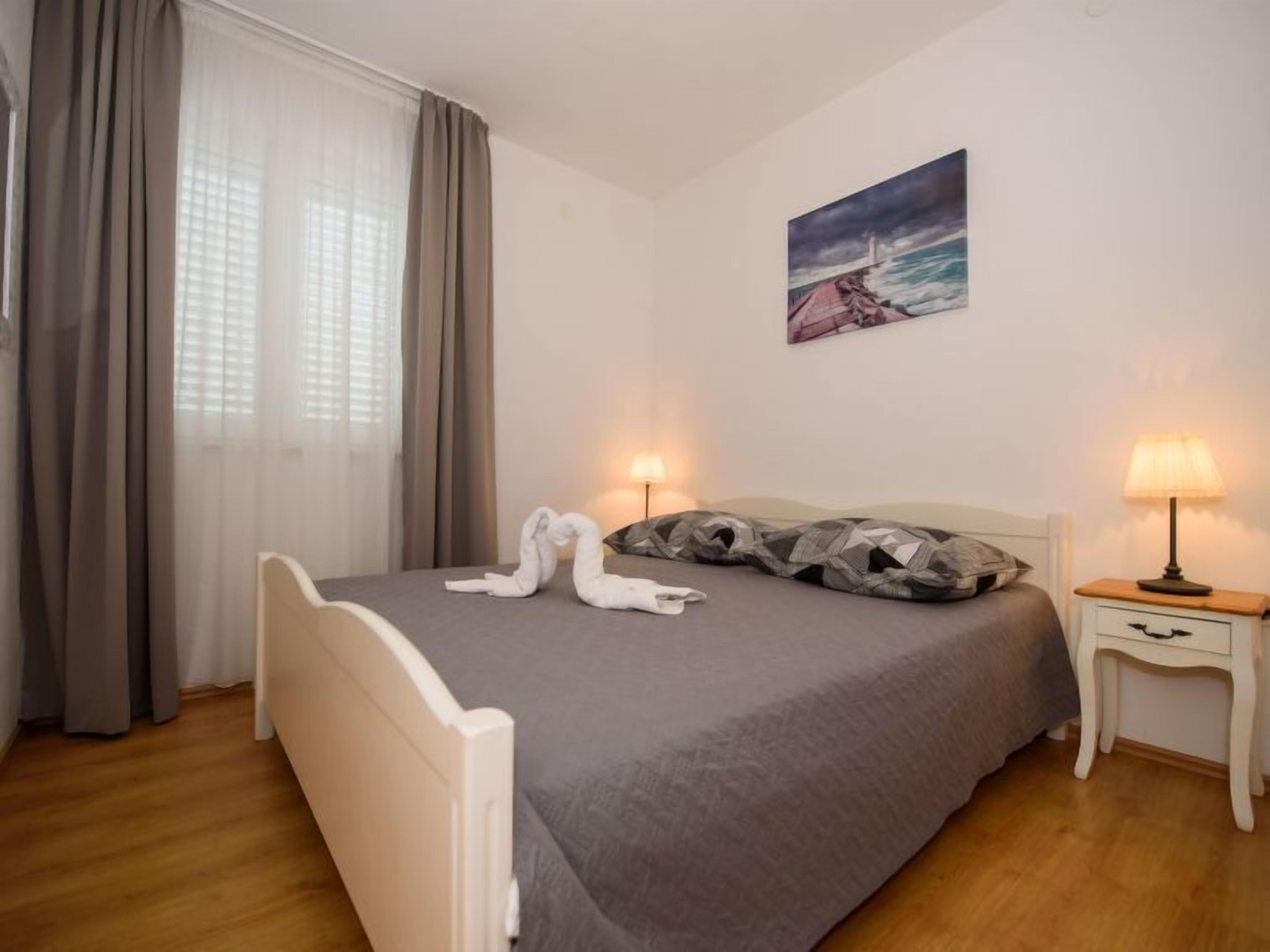 Una camera da letto con un letto, due lampade sui comodini, un quadro e una finestra con tende.