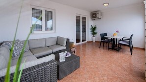 A modern living room with a grey sofa, a small table with chairs, and a potted plant. - Apartment Marina by Interhome (Rogoznica/Ražanj)