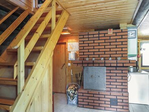 Unes escales de fusta que condueixen a una habitació amb una llar de foc de maó, un rellotge i un paviment de rajoles.