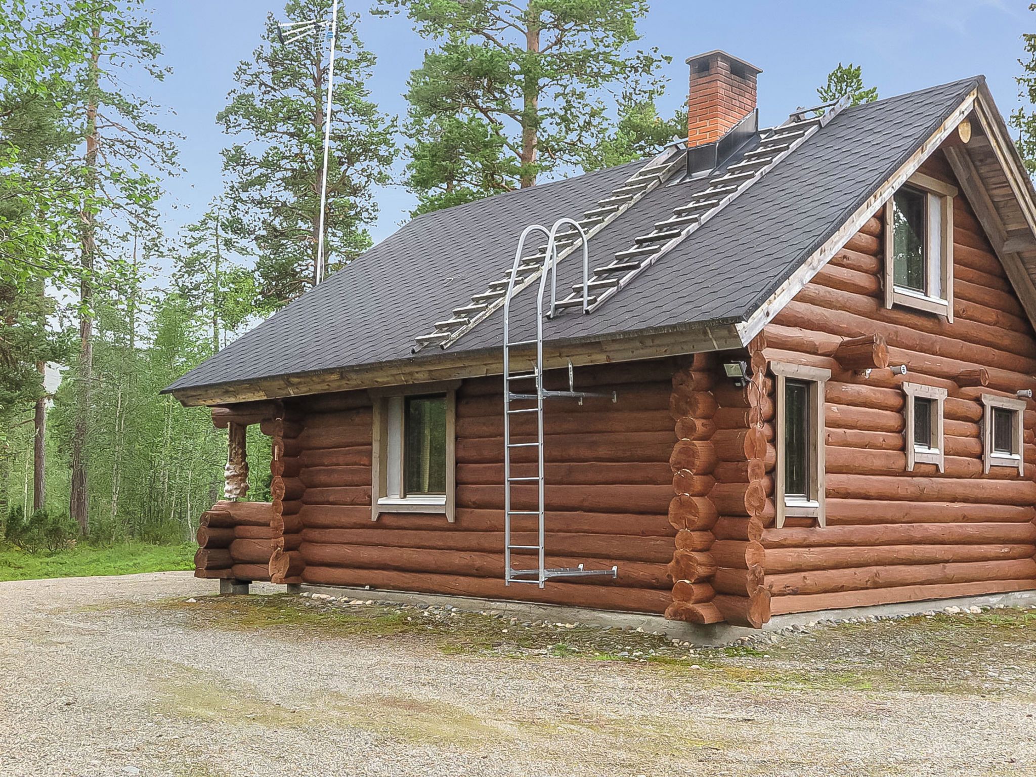 Hirsimökki, jossa on jyrkkä katto, tikkaat ja savupiippu.