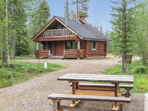 Une cabane en bois avec une véranda, une table de pique-nique devant, entourée d’arbres.
