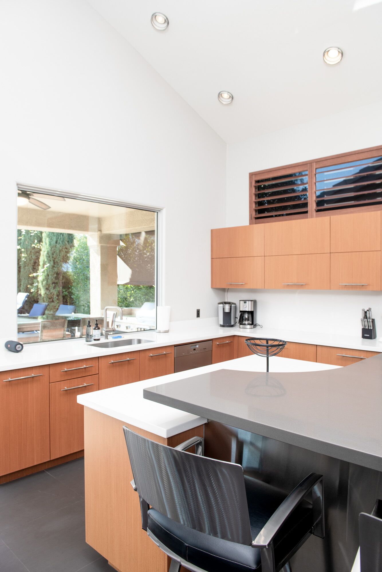 Een moderne keuken met houten kastjes, een groot kookeiland en uitzicht op de omgeving.