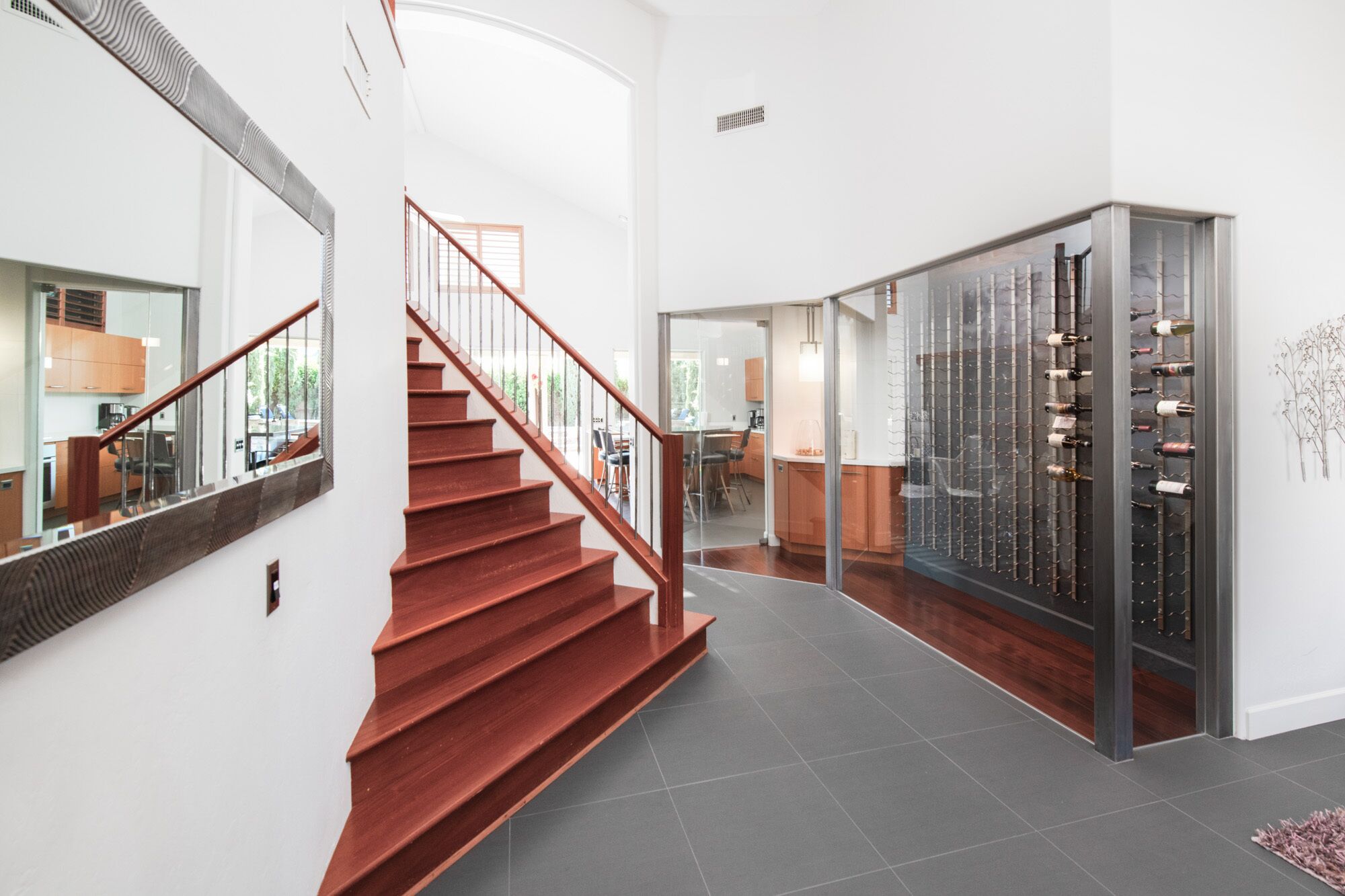 Un intérieur moderne avec un escalier rouge, un meuble à vin et un coin cuisine.
