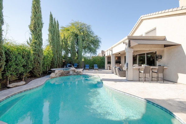 Relax in a serene backyard with a pool, lounge chairs, and barbecue setup.