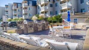 A multi-story residential building with balconies, a barbecue area, and outdoor seating.