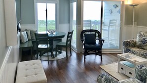 A cozy room with a dining table, chairs, a cushioned bench, a wicker chair, and a small white side table.