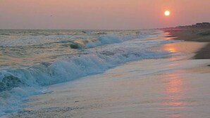 A beach at sunset with waves crashing onto the shore.