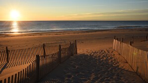 A beach with a wooden fence and a clear view of the ocean.