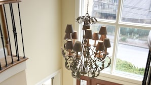 A staircase with a wooden handrail and black balusters, leading to a room with a large window and a chandelier.