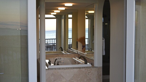A hotel entrance with a glass door, a view of the beach, and a staircase leading to a balcony.