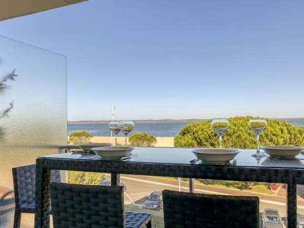 Ein Tisch mit Weingläsern und Schüsseln, mit Blick auf Strand und Meer.