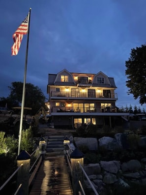 A two-story house with a balcony, a wooden deck, and a flagpole.