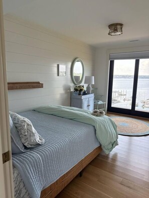 Un dormitorio con una cama grande, un aparador, un espejo y vista al agua.