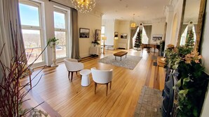 A spacious living room with a large window, a grand piano, and a Christmas tree. - Governor's Mansion Inn (Madison)