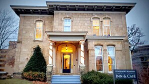 A stone building with a grand entrance, a sign for 'Governor's Mansion Inn & Cafe', and a Christmas tree in the foreground. - Governor's Mansion Inn (Madison)