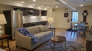 A modern kitchen with stainless steel appliances, a dining area with a table and chairs, and a living room with a sofa and a coffee table. - Governor's Mansion Inn (Madison)