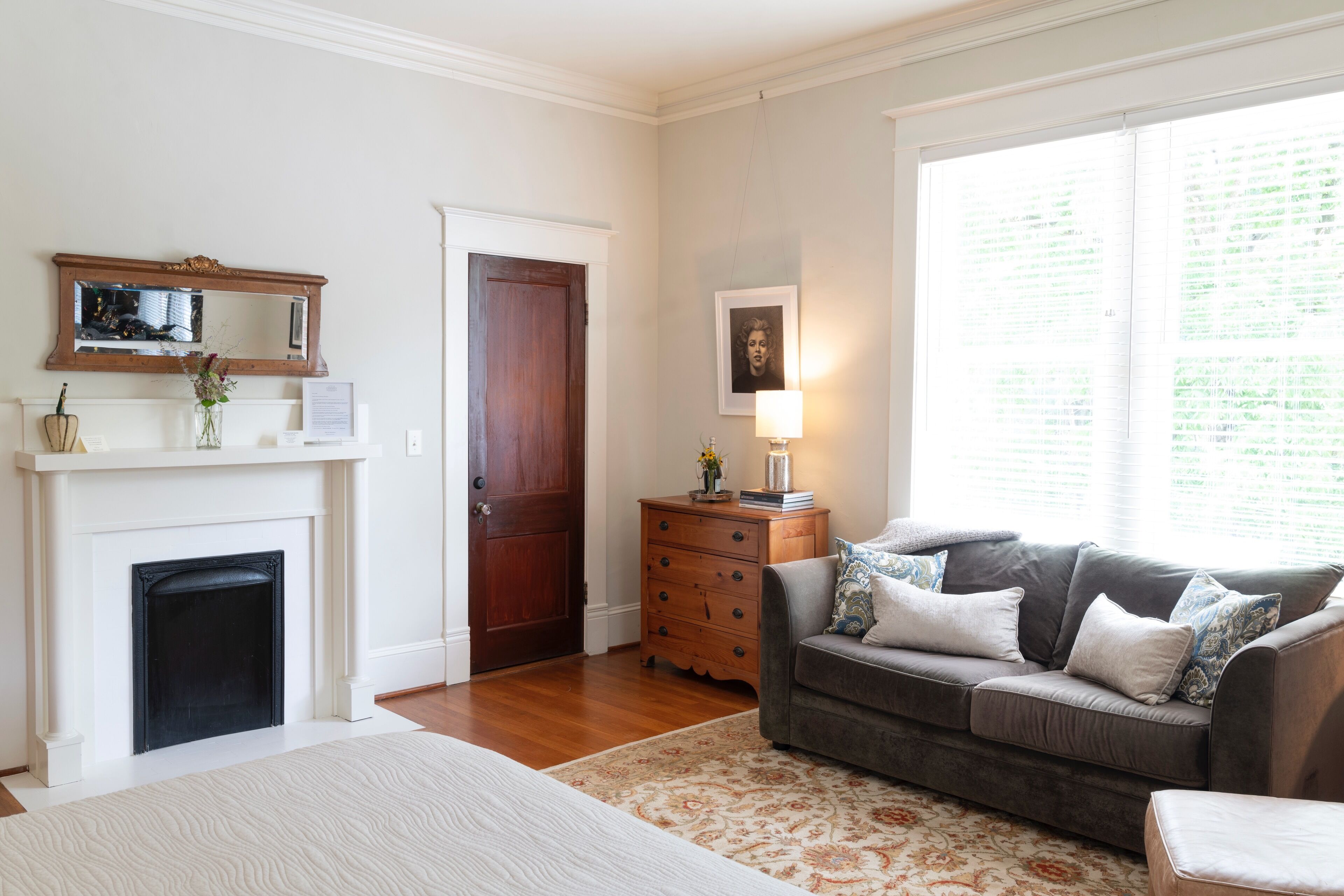 A living room with a fireplace, a sofa, a wooden cabinet, and a large window.