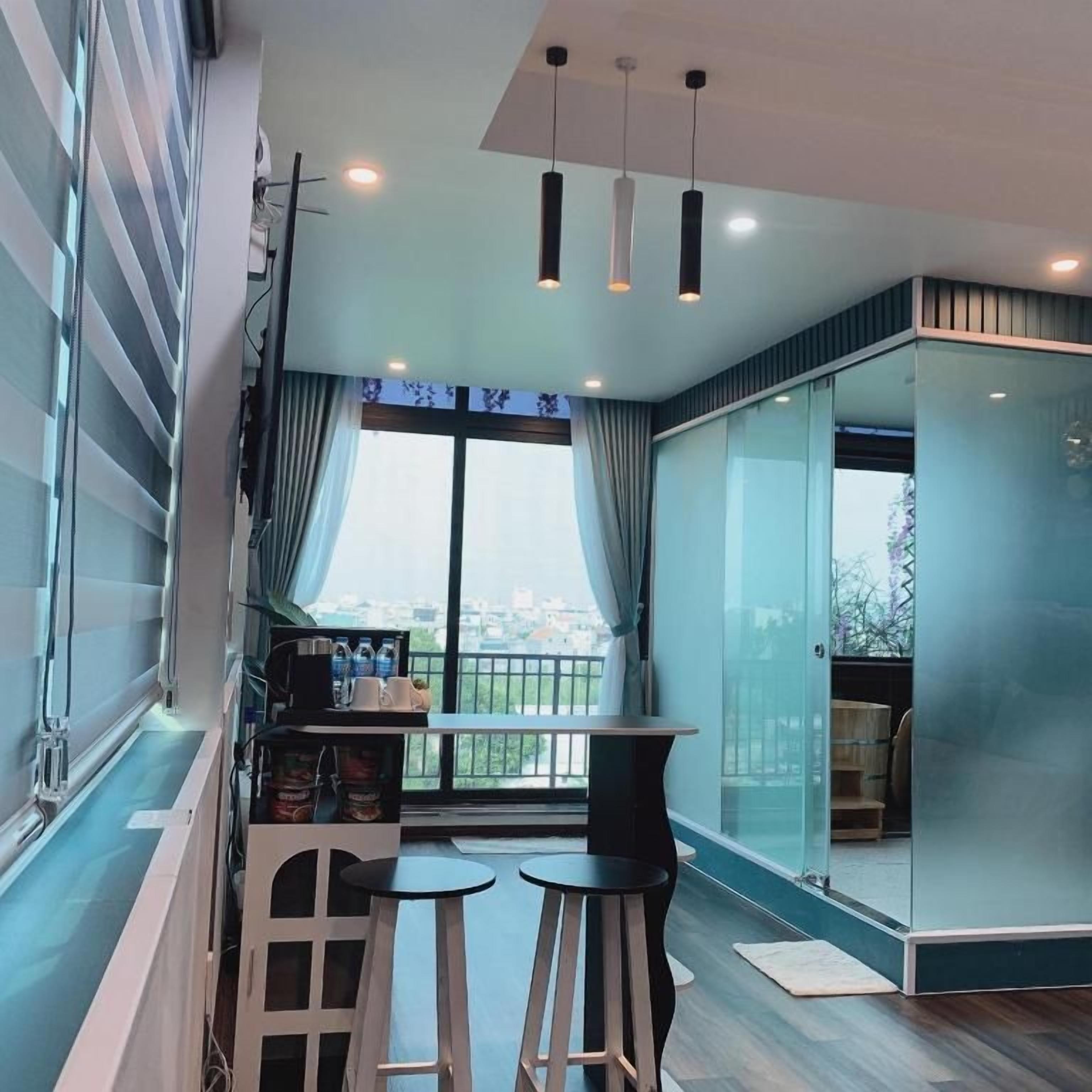 Un interior moderno con área de cocina, un comedor con taburetes y un amplio ventanal con vistas.