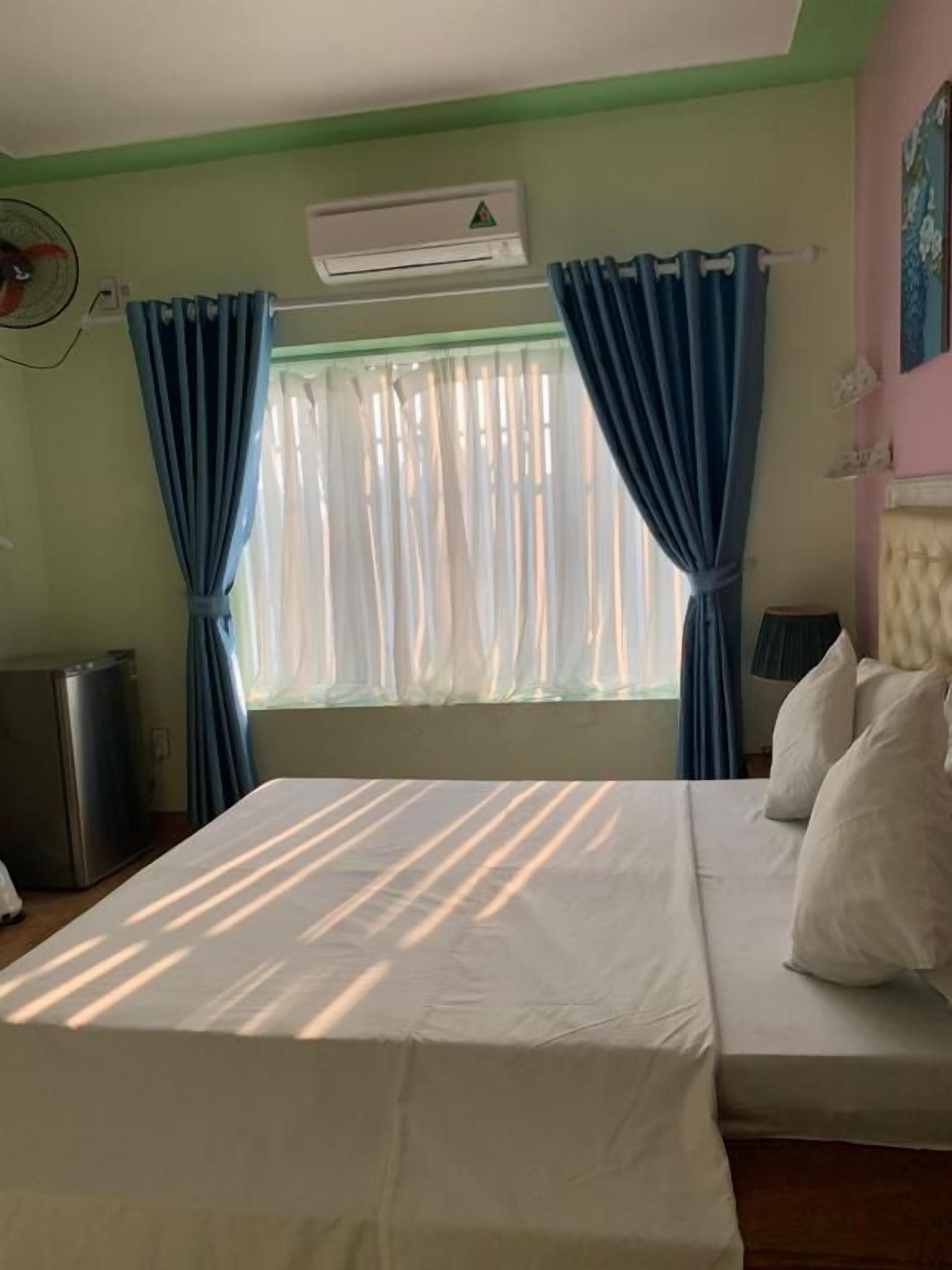 A room with a bed, a window with curtains, an air conditioning unit, and a small heater.