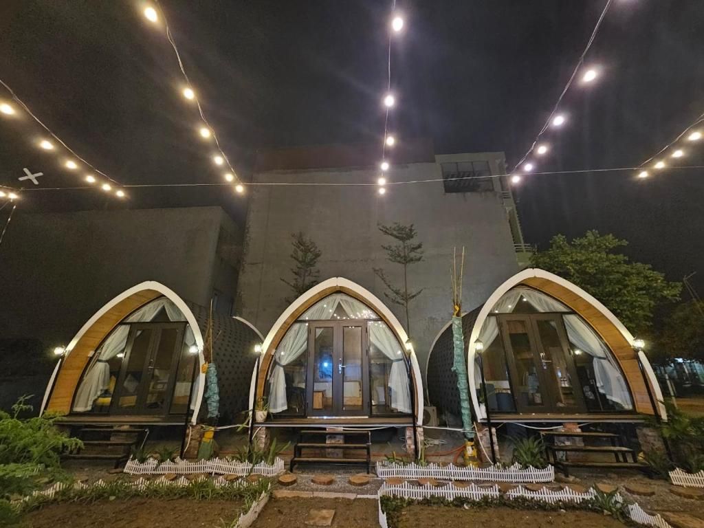Three arched structures with windows, possibly guest rooms, connected by a pathway with a white picket fence.