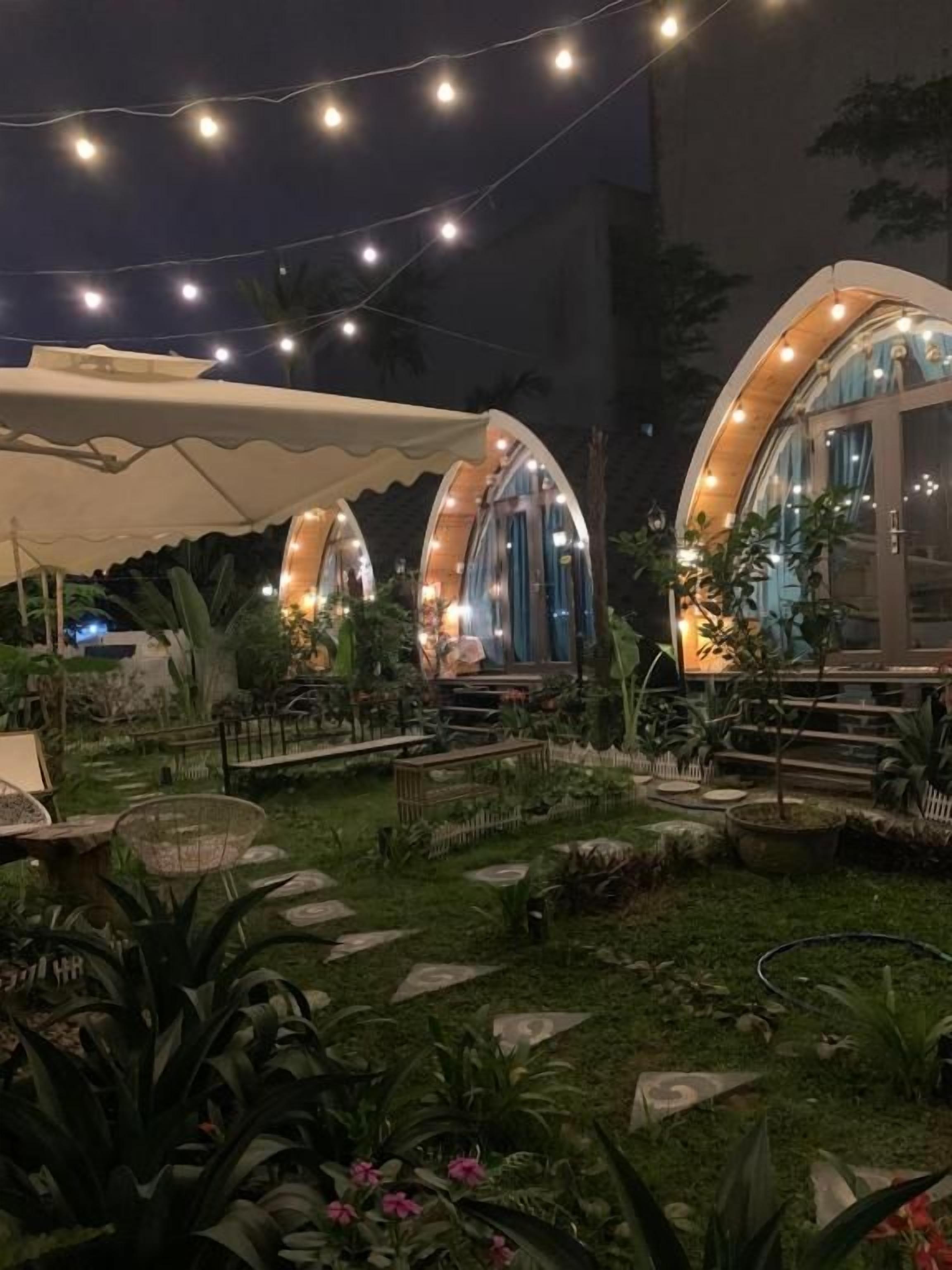 Un jardín con un pabellón, una zona de estar cubierta y un sendero.