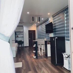A modern kitchen with a refrigerator, bar stools, and a dining area. - Mio Hotel (Hai Phong)