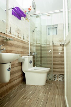 A bathroom with a toilet, sink, and glass-enclosed shower. - Mio Hotel (Hai Phong)