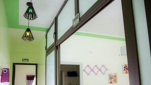Una habitación de hotel con una decoración en tonos verde y blanco, una cama, un baño con ducha y una escalera que lleva a otro piso.