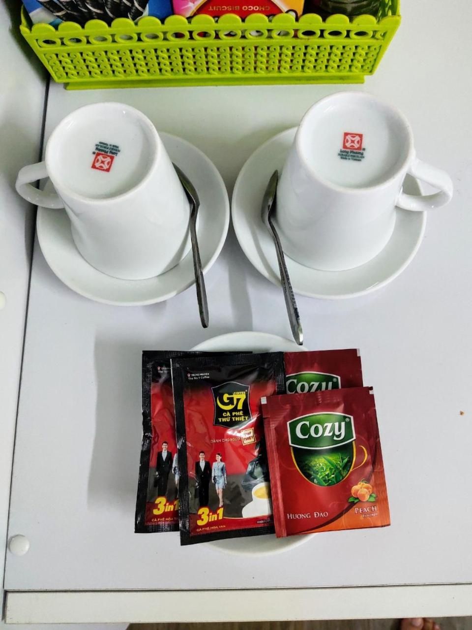 Una mesa blanca con dos tazas y platillos blancos, dos cucharas de metal y dos sobres de té.