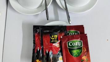 Una mesa blanca con dos tazas y platillos blancos, dos cucharas de metal y dos sobres de té.
