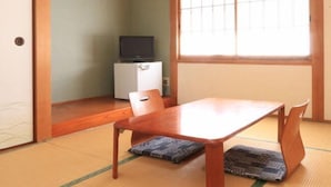 Une pièce de style japonais traditionnel, avec un sol recouvert de tatamis, une petite table en bois et une porte coulissante.