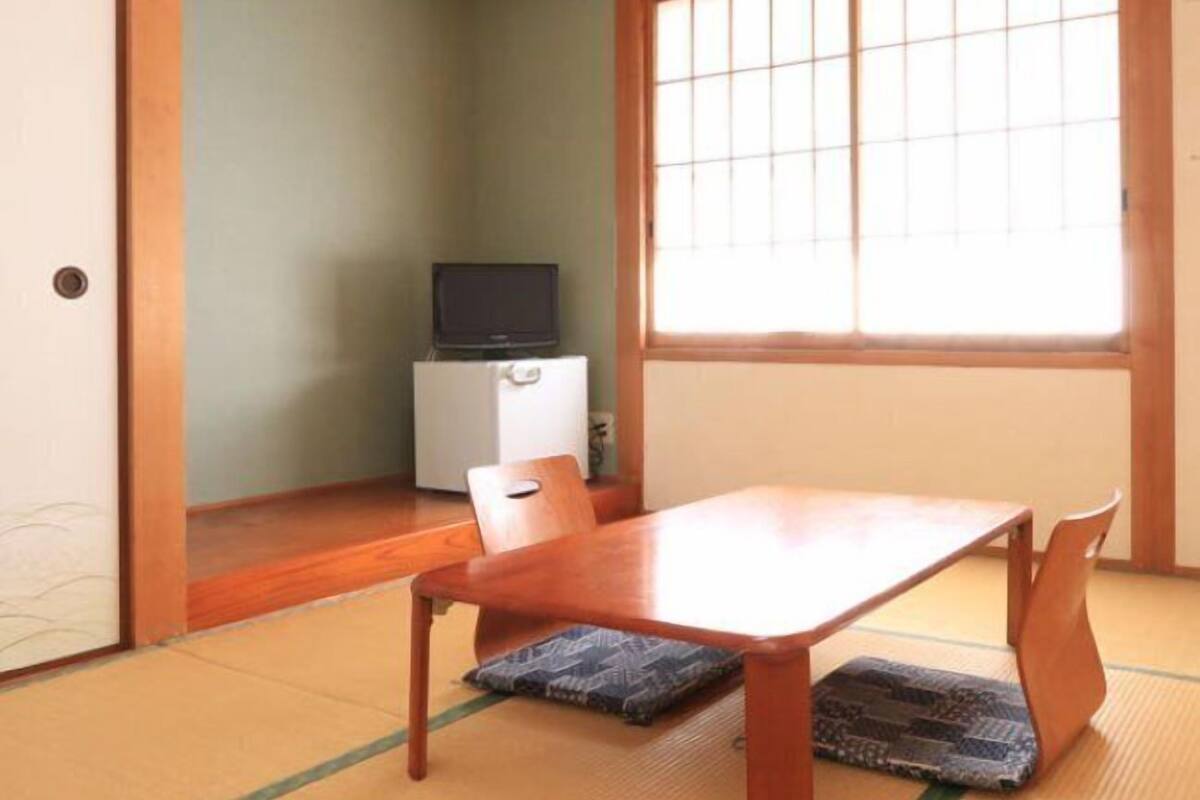 Een traditionele Japanse kamer met tatami vloerbedekking, een lage houten tafel en een schuifdeur.
